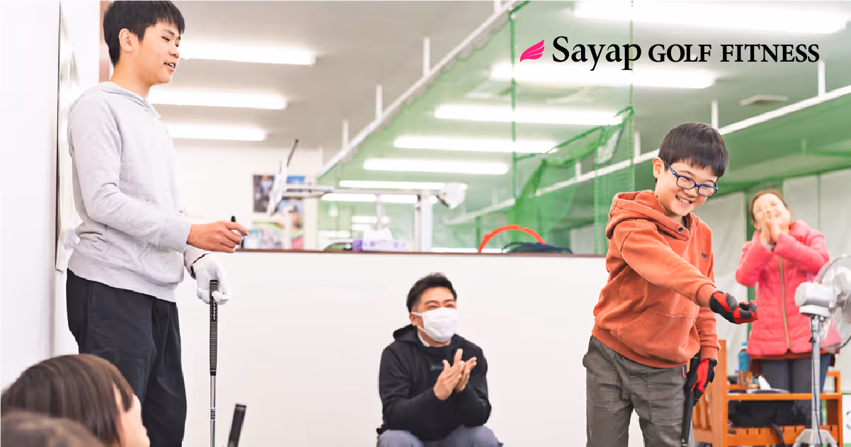 室内パター練習で楽しそうにゴルフをしている子供たちと指導する大人。