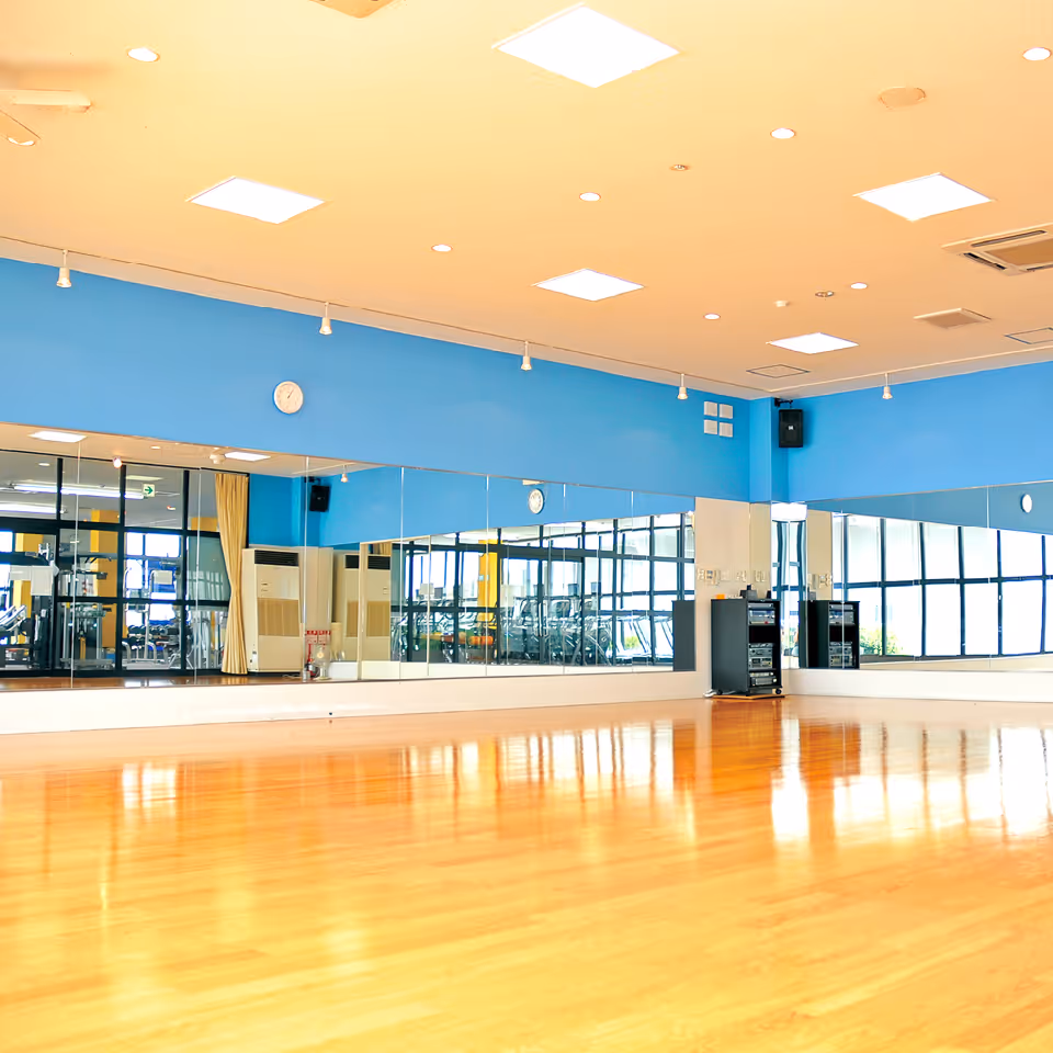 広くて明るいダンススタジオ、青い壁、鏡張りの壁と木製の床。