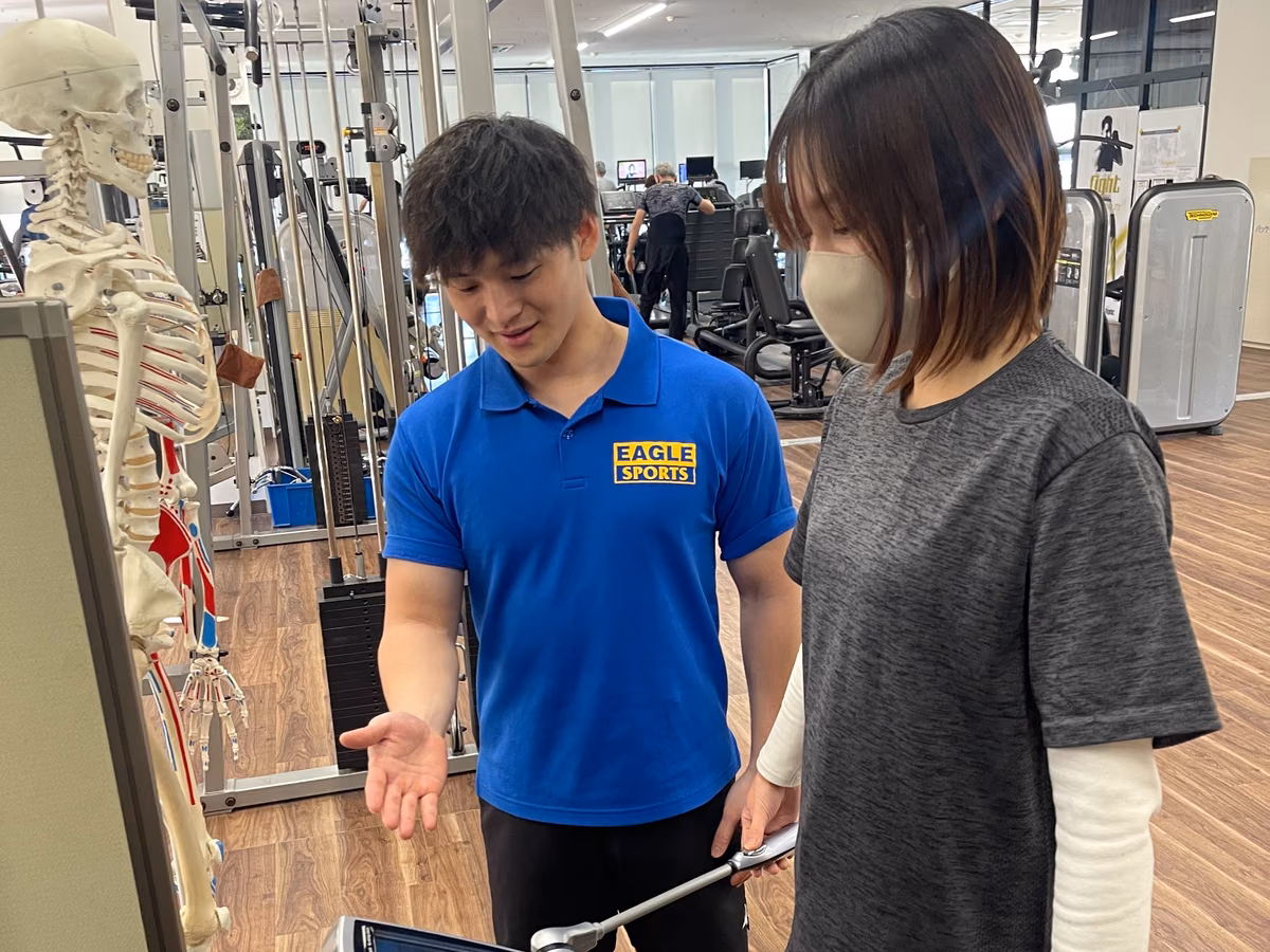 体組成計 InBody の前に立つ会員と、機器を手で示すトレーナー。