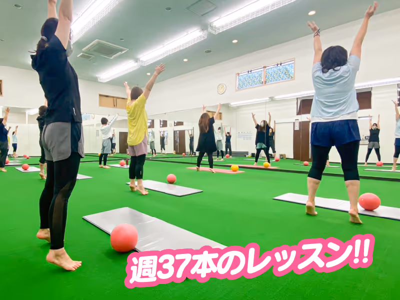 ヨガマットの上で赤いボールを使いながら足を上げて腕を伸ばす運動をしている複数の人々。