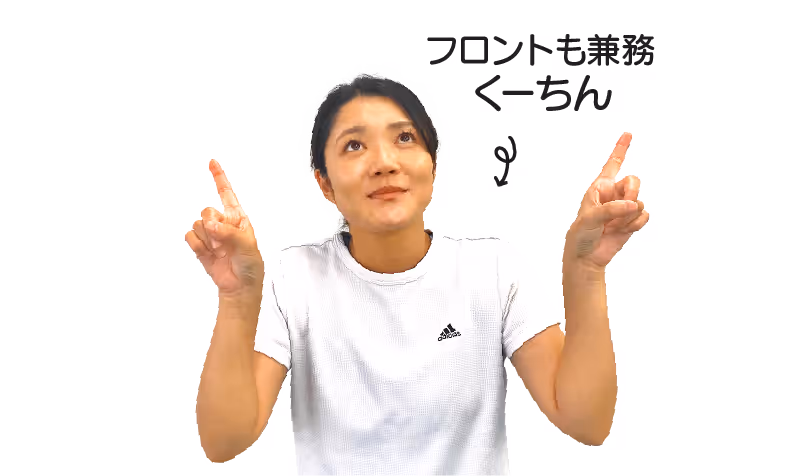 白いアディダスのTシャツを着て、両手の人差し指を上に向けて見上げている女性。