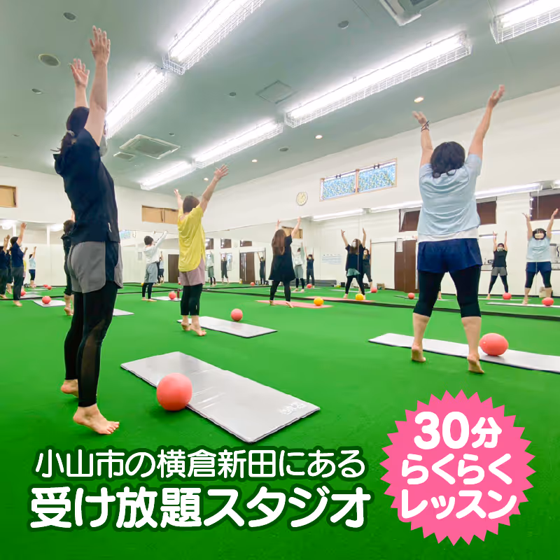 グリーンの床のフィットネススタジオでヨガマットの上に立ち、腕を上げてストレッチをする複数の人々。